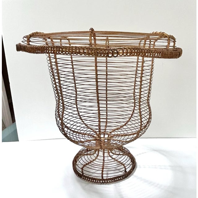 An antique French twisted wire urn planter with a flared rim, coiled detailing, and raised pedestal base. The warm...
