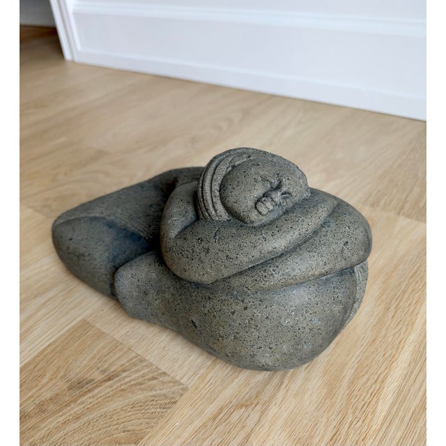 A wonderful vintage modernist sculpture of a reclining woman, hand-carved from substantial gray stone with natural dark...