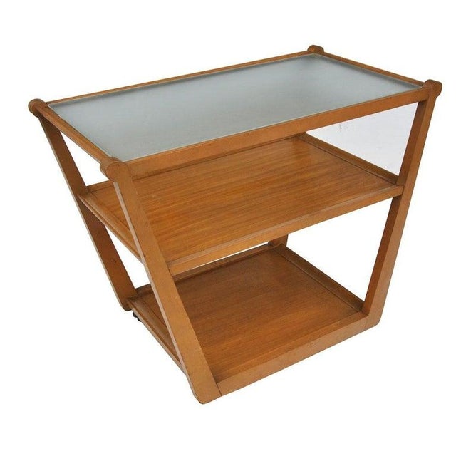 A beautiful rolling bar cart as part of Edward Wormley's Precedent series. Blonde wood, 3 tiered rolling cart with glass...