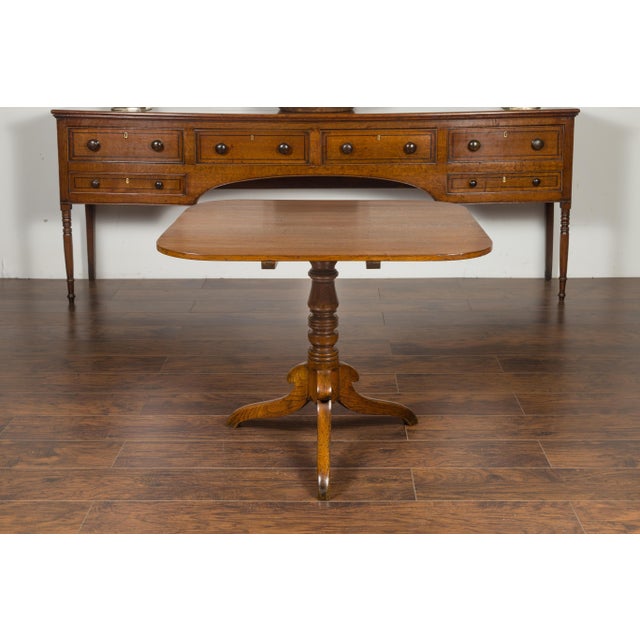 An English oak tilt-top table from the late 19th century, with pedestal tripod base. Created in England during the third...