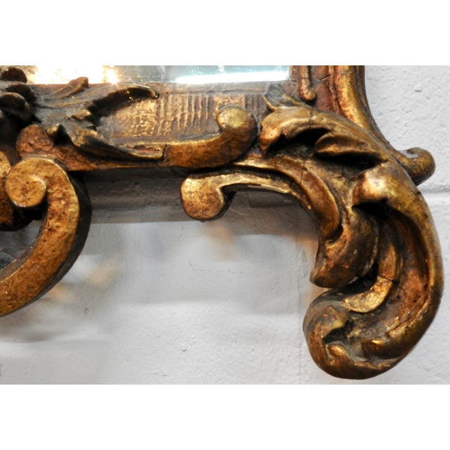 A gorgeous basket of flowers sits atop this ornate mirror from France in the late 19th century. The work on the piece is...