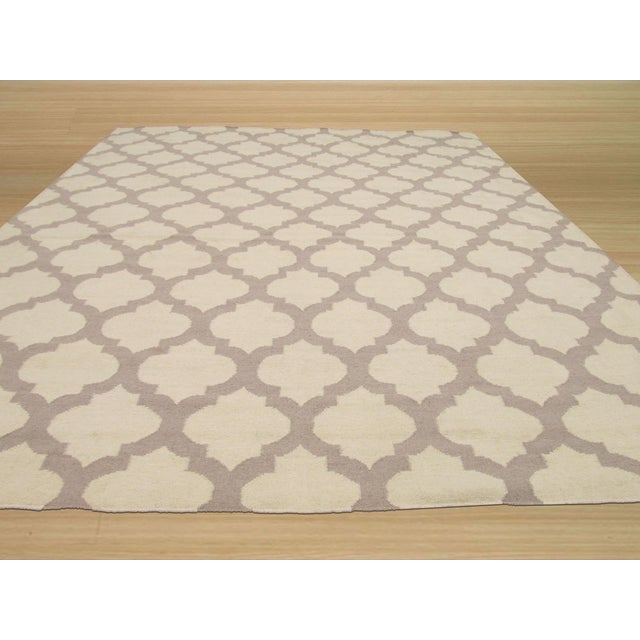 Maya Moroccan Ivory Flatweave Wool Rug, Country of Origin: India. This contemporary flatweave piece draws inspiration from...