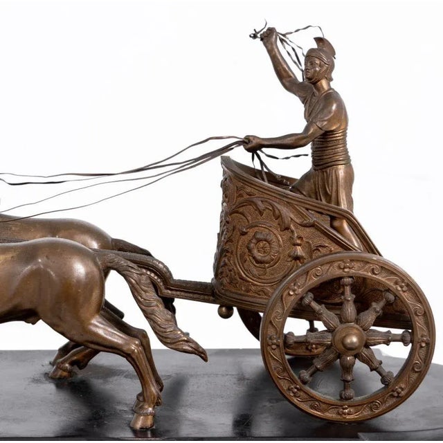 French Patinated Bronze and Black Slate Chariot Clock, late 19th century, of rounded rectangular form, surmounted by a...