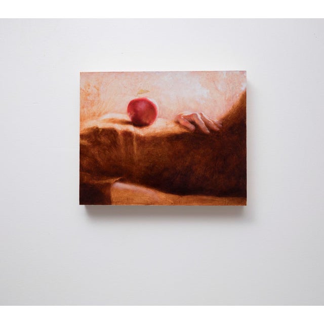 The artwork presents a serene composition featuring a hand resting on a textured surface, with a single red apple perched...