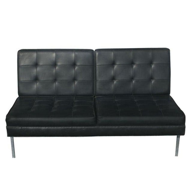 A mid century modern armless settee in the style of Florence Knoll. Chrome base with angled rear legs and tufted black...