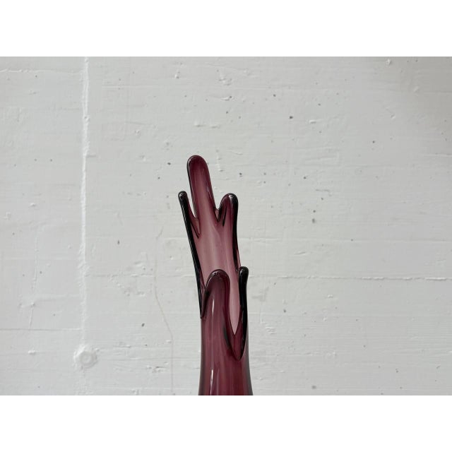 An elegant, mouth-blown Murano glass vase from the 1950s, featuring a sculpturally curved silhouette and a deep violet...