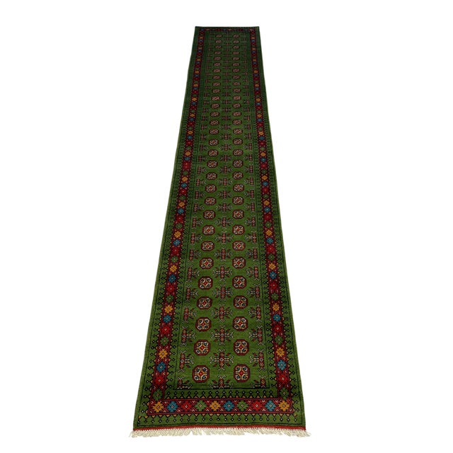 A vivid green field carries two rows of repeating octagonal motifs, with smaller geometric accents between them. Red...