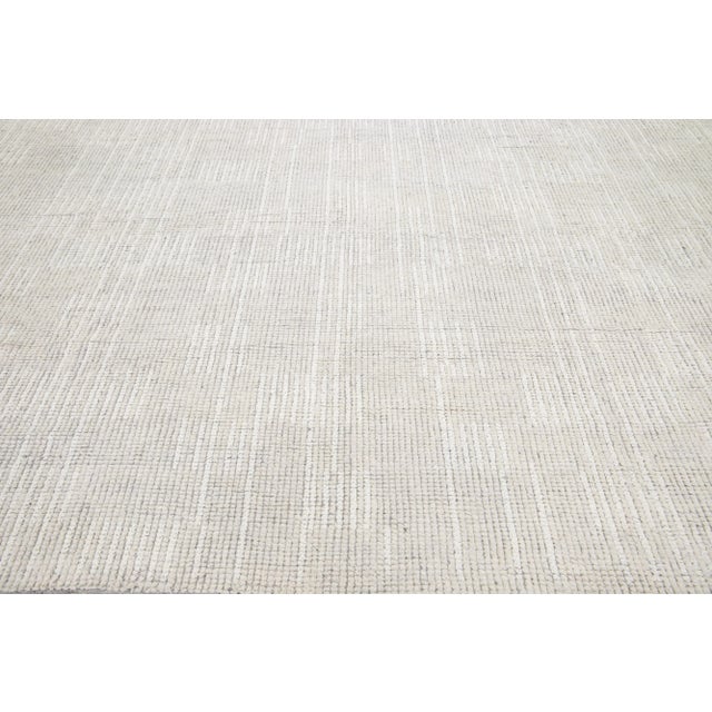 Beautiful modern Moroccan-style hand-knotted wool rug with an ivory color field. This piece has white accents with an...