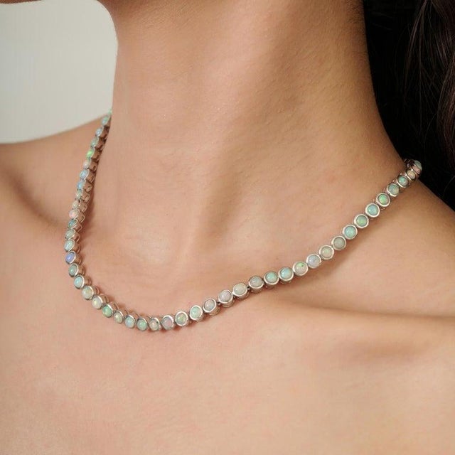 This tennis necklace features a continuous line of natural opal gemstones, totaling 14.34 carats, beautifully set in 925...