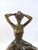 This bronze statue captures the delicate beauty of a ballerina seated gracefully as she adjusts the bun atop her head....