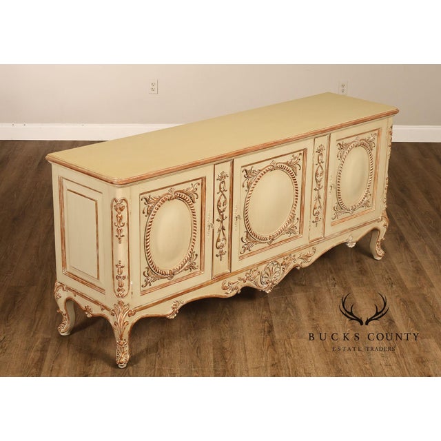 Decorative French Provincial style sideboard featuring an elegant cream-painted finish with antiqued distressing and...