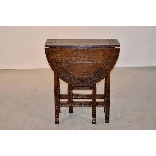 19th century English oak gate-leg table with a hand-carved border around the top, following down to hand carved and turned...