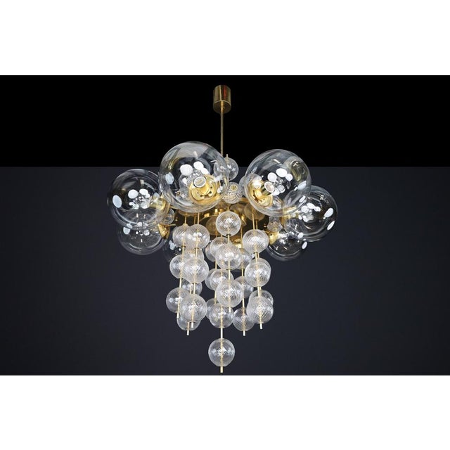 An exceptional set of six monumental czech chandeliers, combining sculptural brass construction with clear bohemian glass...