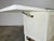 Mid-century drop-leaf server on casters having original white lacquer with cane front doors, ample cabinet storage and a...