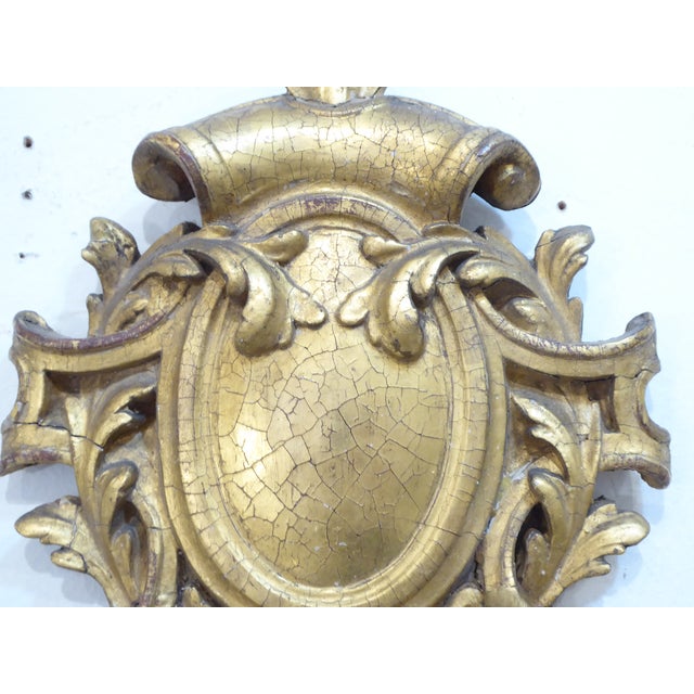 This decorative wall plaque is formed of plaster on wood, with a crackled gold finish.