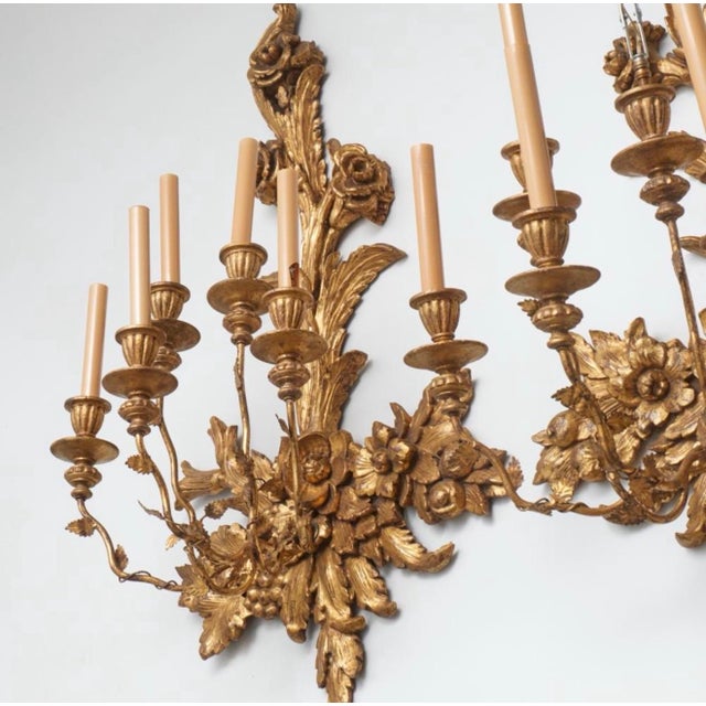 An impressive and exceptionally decorative pair of monumental mid-20th-century giltwood five-light wall sconces,...