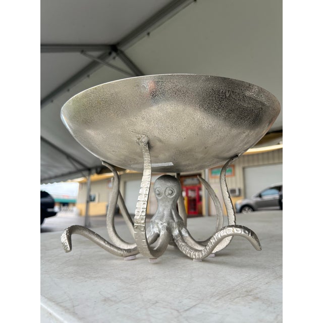 Bring a dramatic splash of coastal elegance to your table with this striking cast metal octopus pedestal serving bowl....