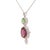 This platinum pendant showcases an oval tsavorite garnet above a larger pink‑red garnet, each encircled by a diamond halo....