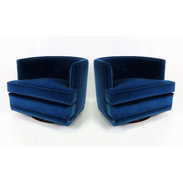 Luxurious pair of swivel lounge chairs freshly upholstered in a blue velvet. Attributed to Harvey Probber. They feature a...