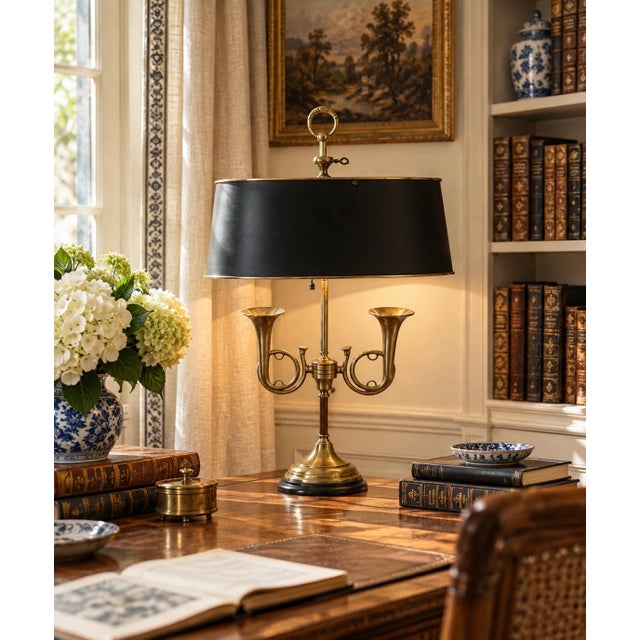 A classic bouillotte lamp rendered in warm brass, distinguished by its sculptural double horn base and clean, tailored...