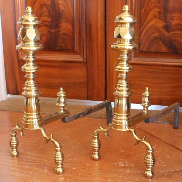 A jaunty pair of fine quality andirons, with an interesting version of the typical spurred legs resting on ball feet....