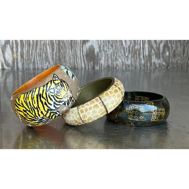 This set of three hand-carved wooden bangles brings together a striking mix of painted, patterned, and etched designs,...