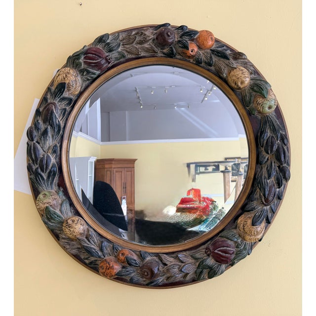 A round LaBarge beveled mirror framed within a richly carved fruit-and-foliage frame in warm, hand-painted tones.