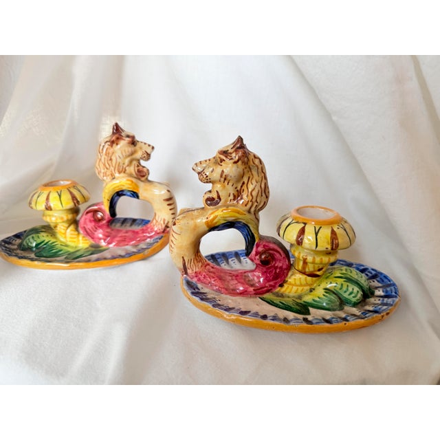 Pair of vintage 1950s Italian majolica chambersticks, each featuring a sculptural griffin handle with a detailed lion-like...