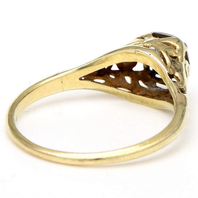 A glittering diamond is surrounded by ornamental yellow gold in this inspiring Art Deco ring. The decorative elements in...