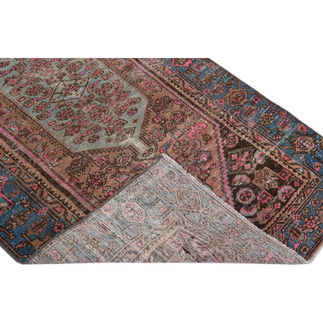 Beautiful vintage Persian distressed hand-knotted wool rug with a pink color field. This piece has a blue frame and beige...
