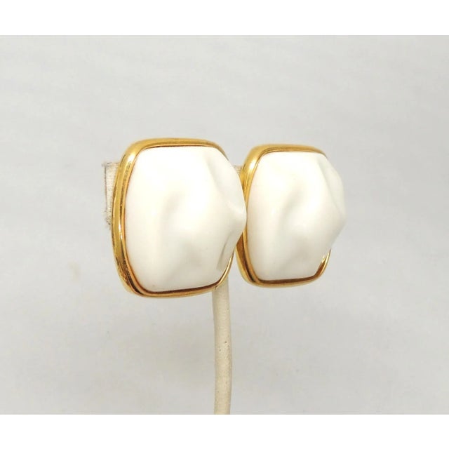 This is part of Chairish’s Costume Jewelry assortment. 1970s or early 1980s modernist goldtone white molded resin clip...