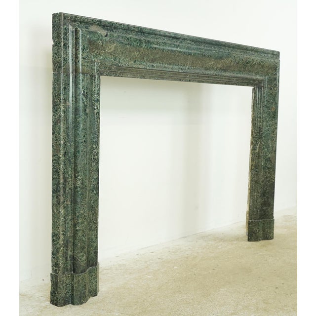 This mantel is made from dark green marble with natural patterns of gray running through it. It has a classic Bolection...