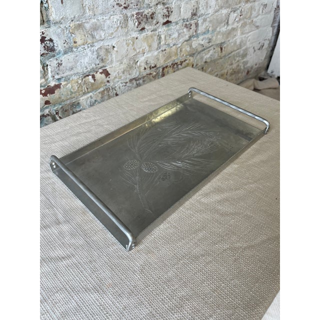 Bring a touch of rugged elegance to your space with this vintage metal tray, featuring an etched pine branch and pinecone...