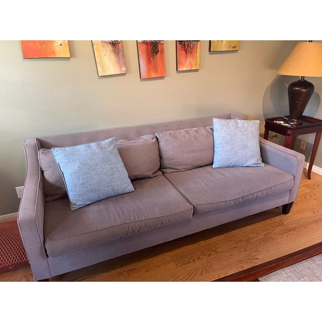 The Cameron Crate & Barrel sofa is a standout in any living room, upholstered in a soft, textured gray linen-blend fabric...