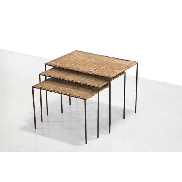 Minimalist set of three nesting tables that can be stacked to save space. The tables are made of black metal and the tops...