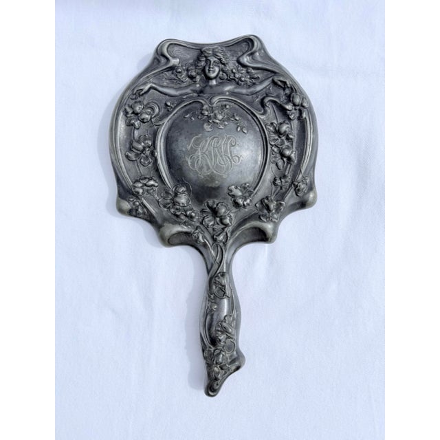 A Beautiful Art Nouveau Silver Plate hand Mirror. Featuring a beautiful Woman with Flowers and intricate design. Has...