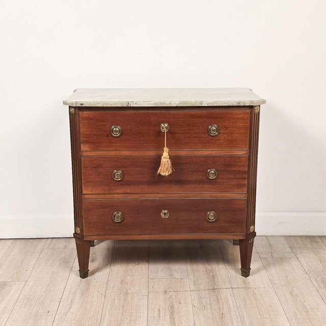 An early 20th-century Swedish mahogany chest of drawers with gilt brass trim and inlay with a marble top, circa 1920.