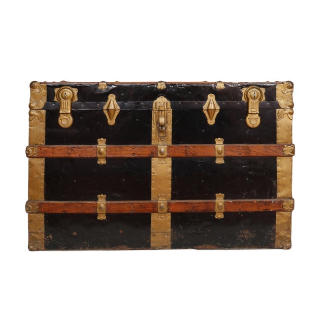 An early 20th century wooden flat top steamer trunk with original leather handles, lid guides and front latches with...