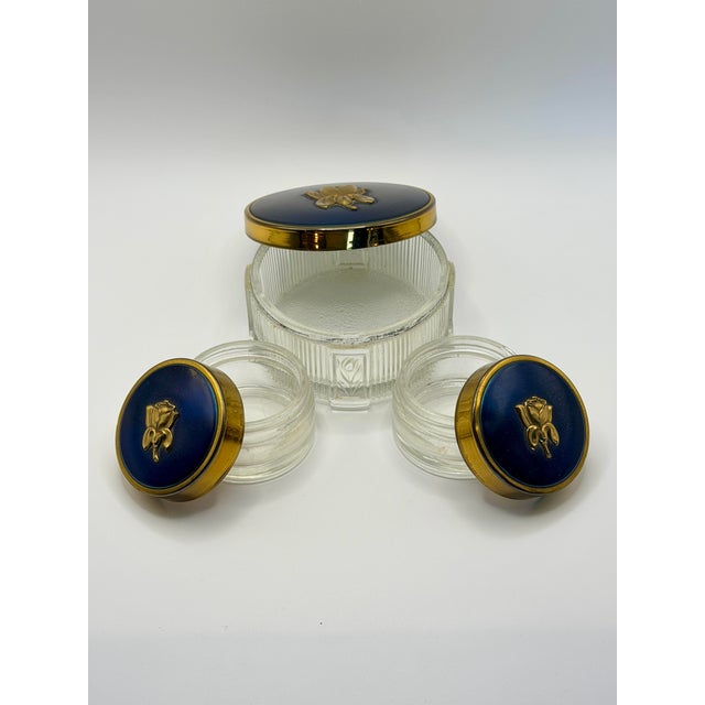 Elegant vintage vanity jar trio featuring ribbed clear glass bodies with deep cobalt blue lids, gold-tone trim, and...