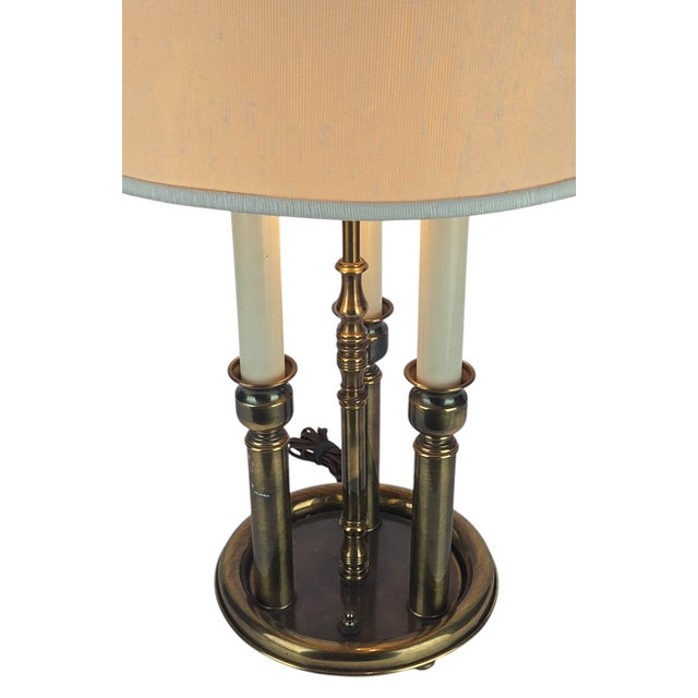 A classic vintage three-light bouillotte lamp in warm antiqued brass, a mid-20th century American interpretation of the...