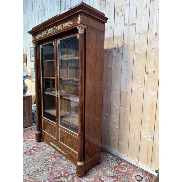 Empire period display cabinet in flame mahogany veneer on a solid oak frame. The two glass doors are framed with beaded...