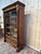 Empire period display cabinet in flame mahogany veneer on a solid oak frame. The two glass doors are framed with beaded...