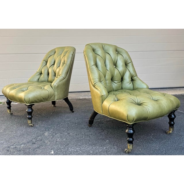 Vintage English Slipper Chairs in beautiful tufted olive green leather on turned wood legs with casters.
