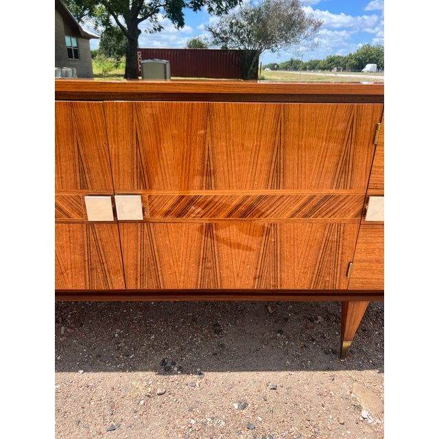 A striking Art Deco sideboard, circa 1940s, featuring beautifully figured light Macassar veneer, clean geometric lines,...
