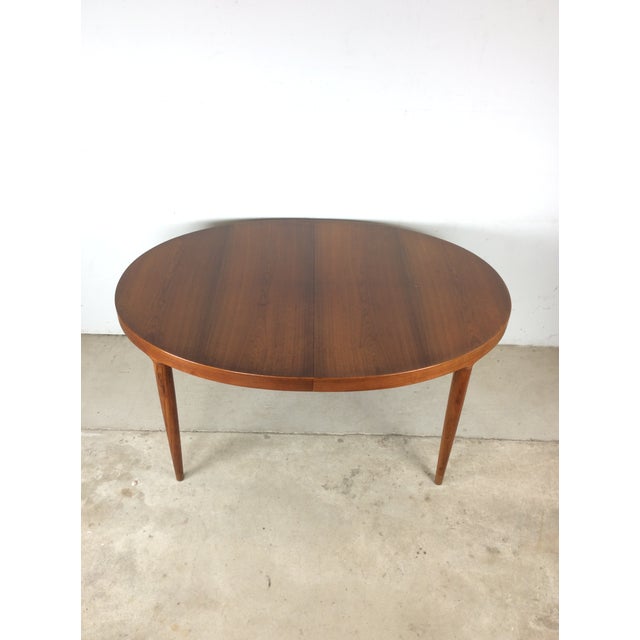 This Danish modern dining table features hardwood construction, original teak finish, unique oval design with three leafs...