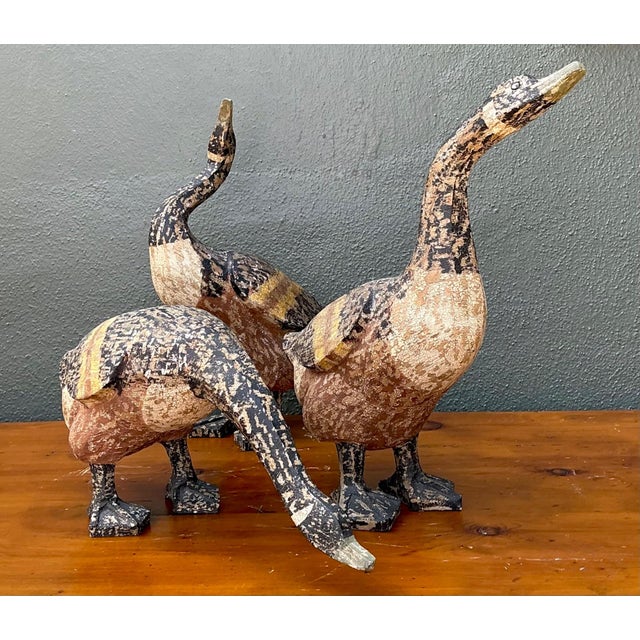 This charming set of three vintage carved wood goose sculptures captures the warmth and authenticity of rustic folk art....