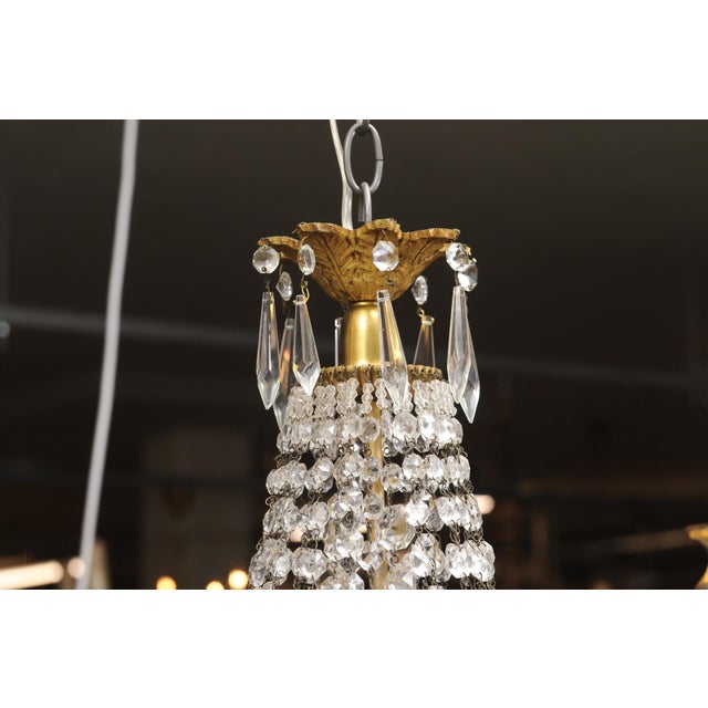 A beautiful example of a French Empire crystal basket chandelier showcasing a finely detailed gilt bronze frame and an...