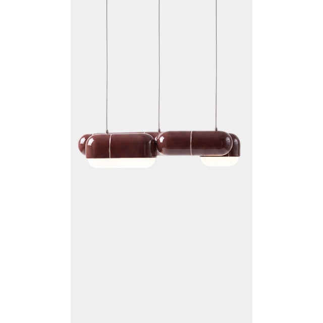 A linear pendant made for the table everyone gathers around. The curved-tile module repeats along its length, so light...