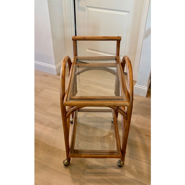 Mid Century rolling cart with a curved rattan frame and 2 glass shelves. In excellent condition.