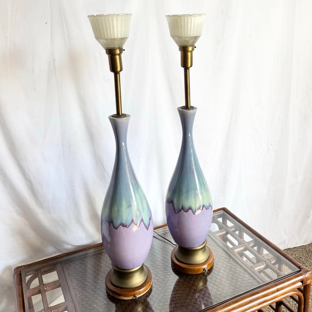 This striking pair of mid century modern ceramic table lamps features elegantly tapered forms finished in a soft lilac...